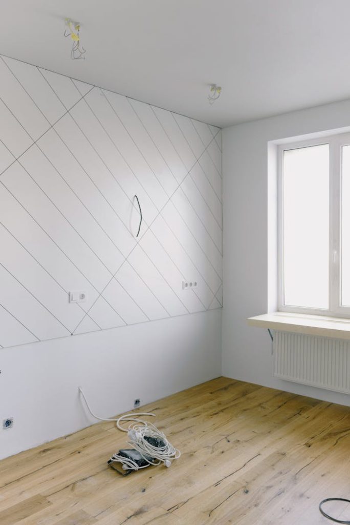 Bright modern room during renovation with wooden floors and white walls.